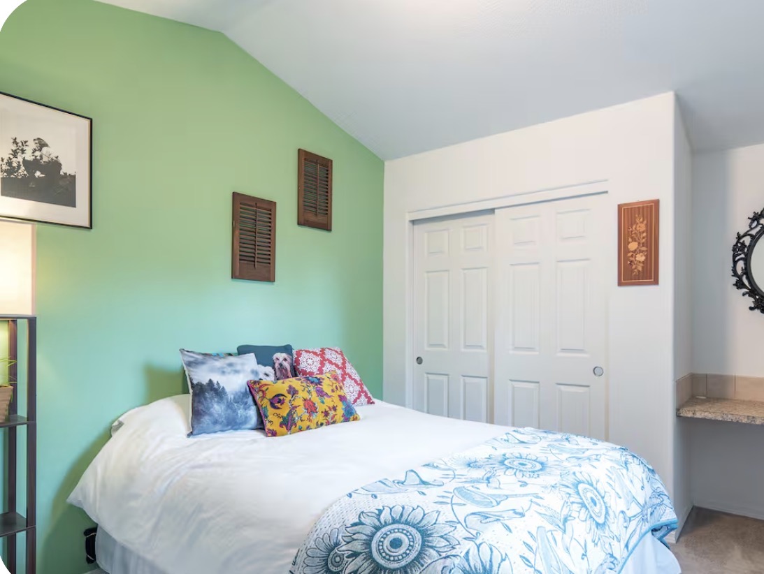 Bedroom with green accent wall and colorful pillows